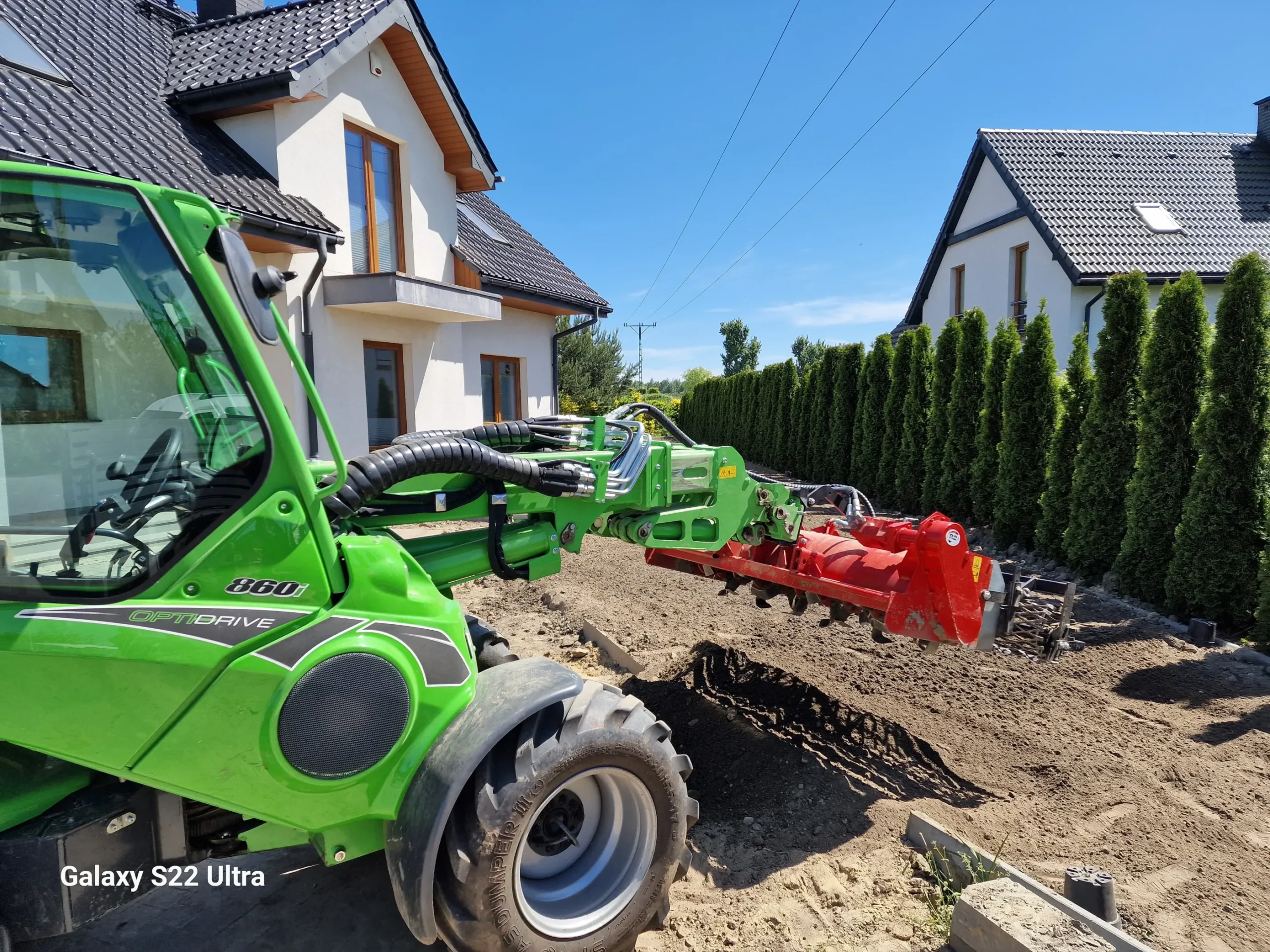 Niwelacja terenu ładowarką z glebogryzarką przed nowoczesnym domem