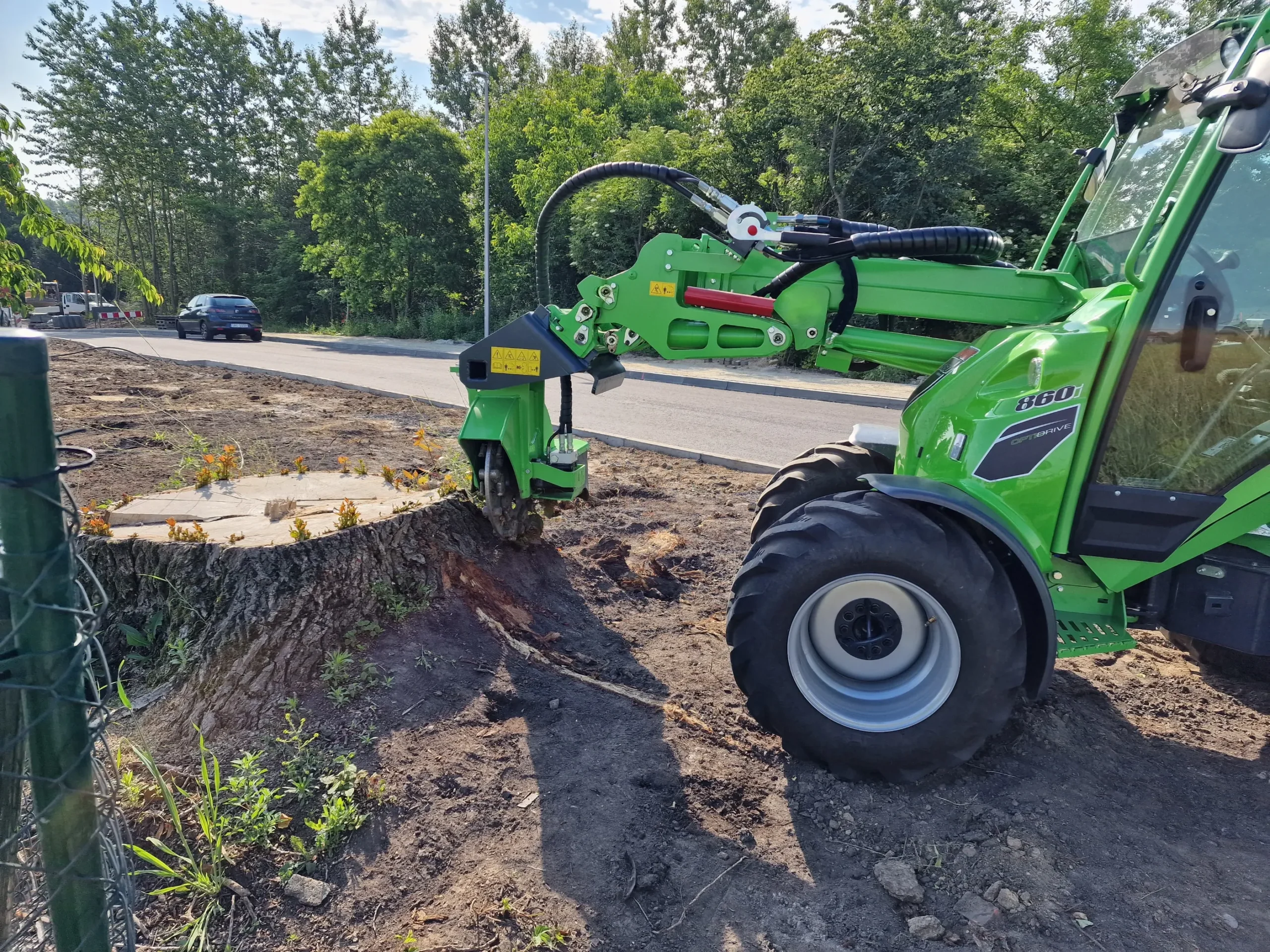 Frezowanie pni ładowarką z frezem hydraulicznym przy krawędzi drogi