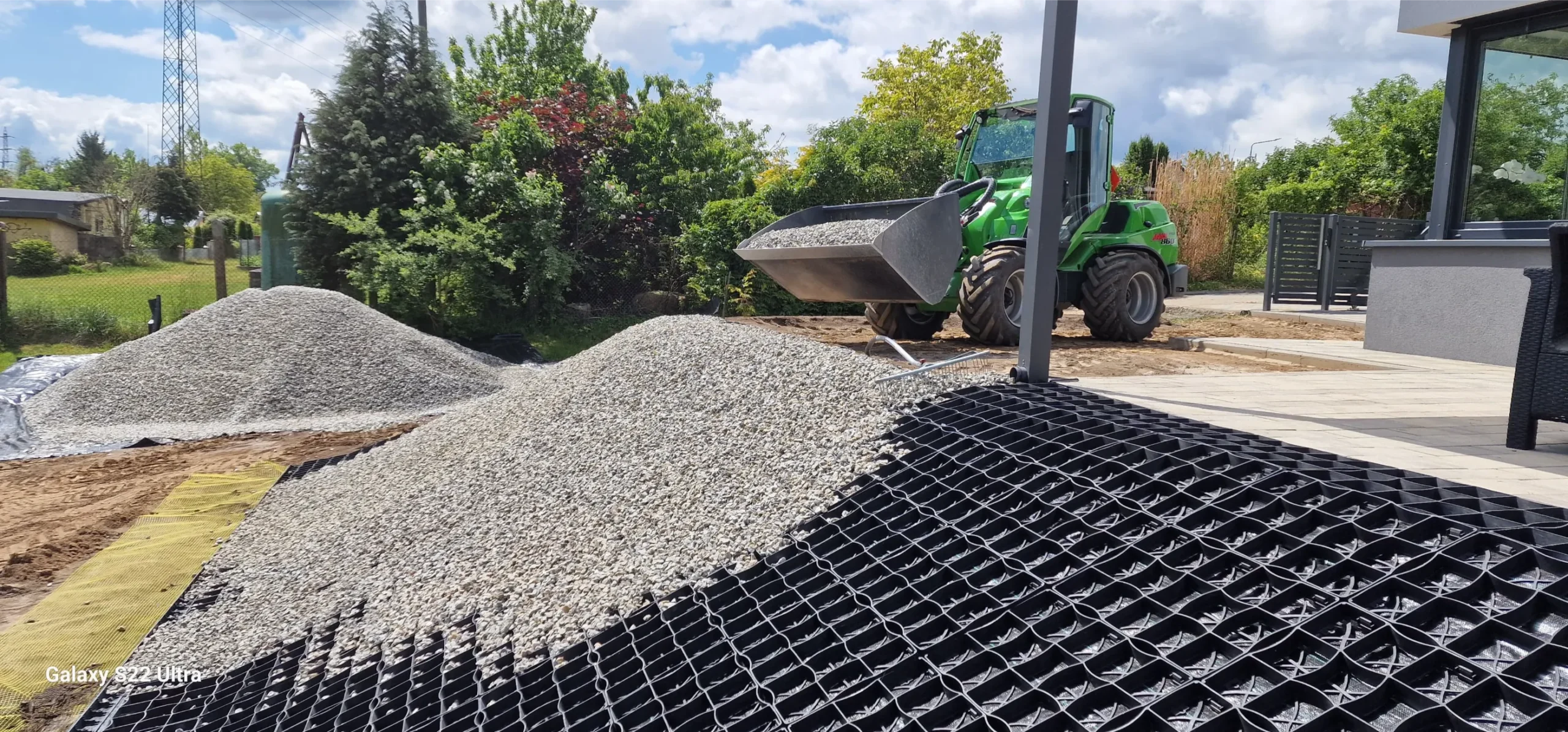Rozwożenie żwiru ładowarką na przygotowaną podbudowę z plastikowej siatki