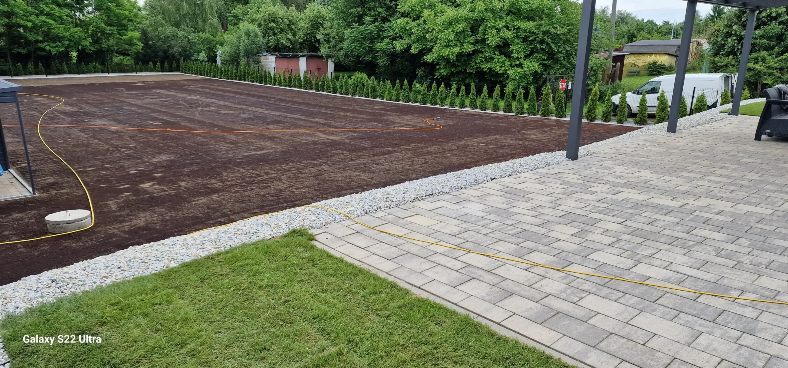 Równo wyrównany teren ogrodu z wymienioną ziemią i kamiennym obrzeżem przed sianiem trawy Przygotowanie terenu