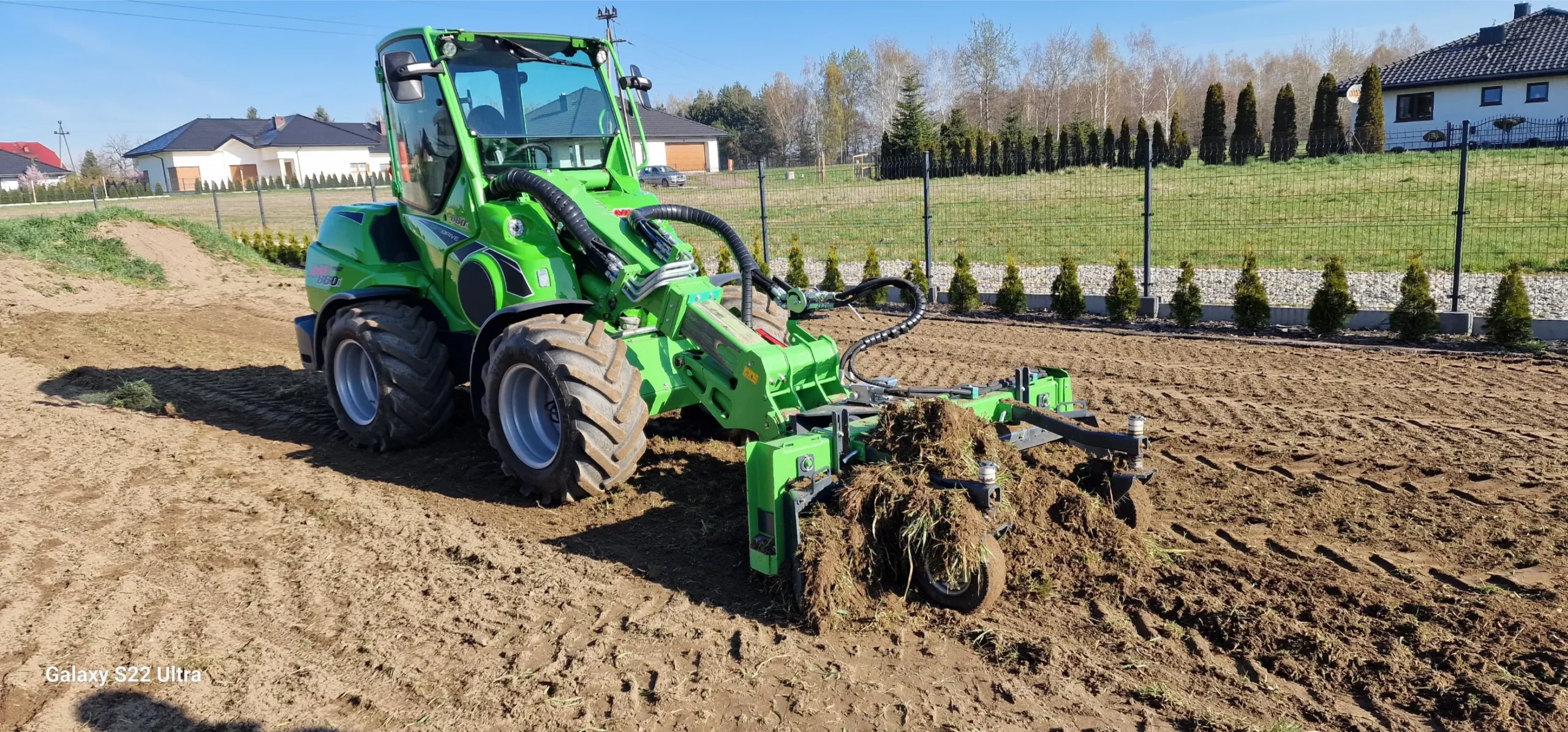 Ładowarka terenowa rozluźnia glebę wokół ogrodu przy pomocy zgrabiarki hydraulicznej Praca zgrabiarką hydrauliczną